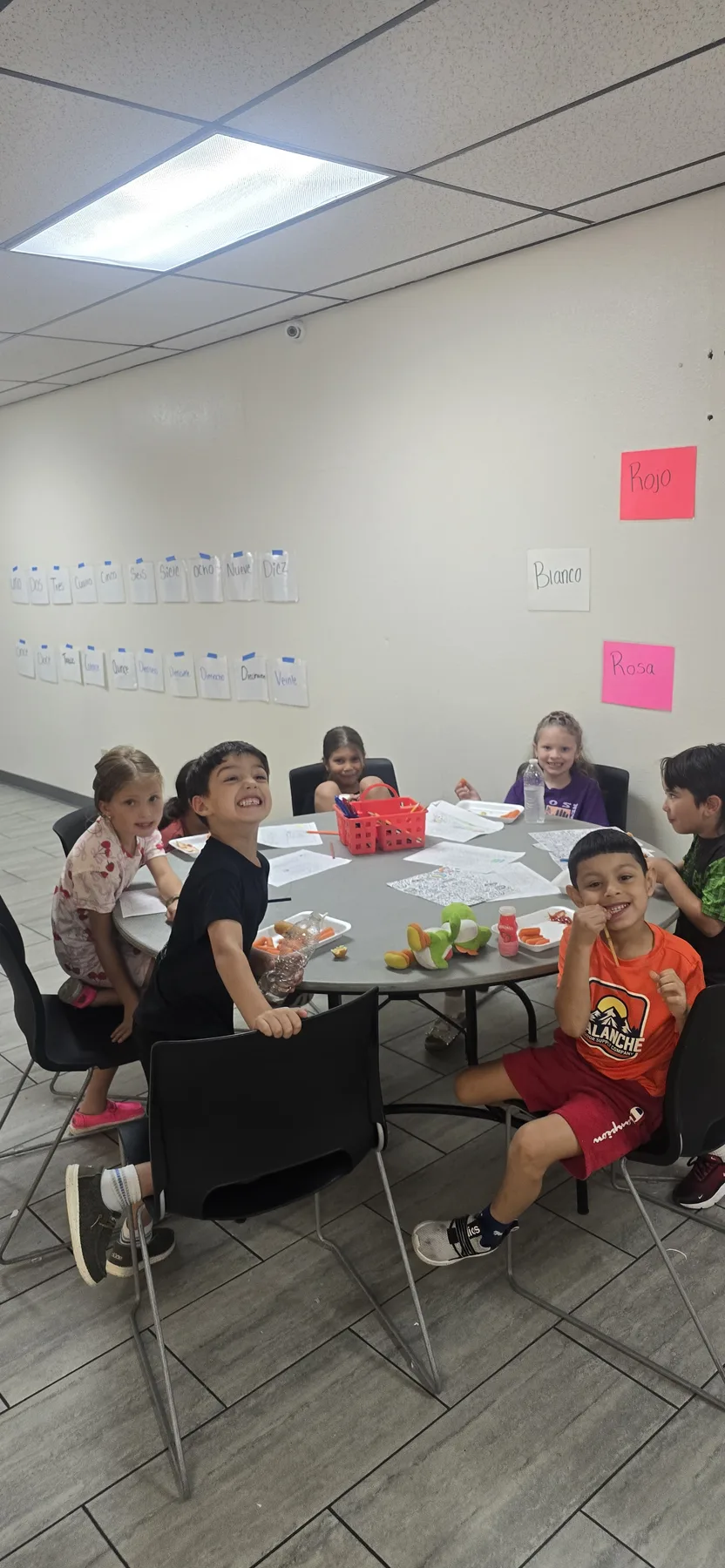 Campers smiling together around a table during Spanish games